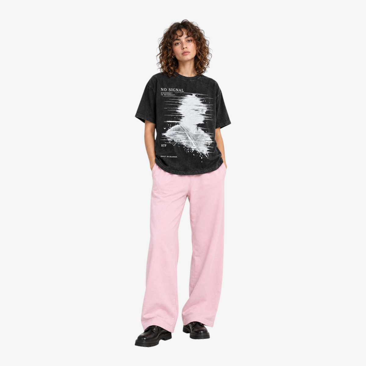 STF No Signal graphic T-shirt in washed black — Female model front with pink wide-leg trousers