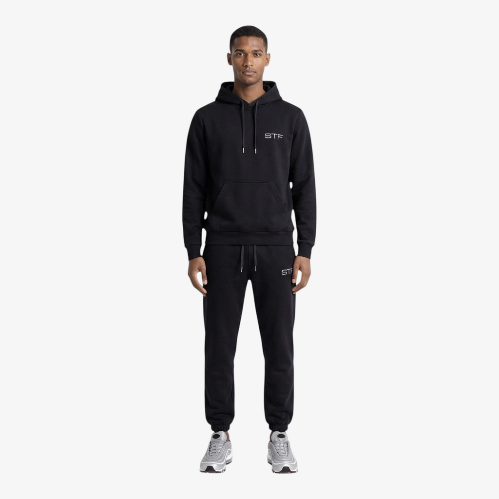Model wearing a Seejthreadsflames (STF) black heavyweight cotton tracksuit with oversized hoodie and relaxed joggers.