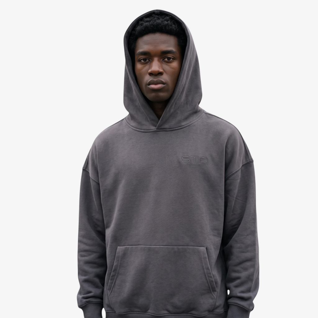 Model wearing a Seejthreadsflames (STF) charcoal grey heavyweight oversized French terry hoodie with chest embroidery.
