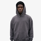 Model wearing a Seejthreadsflames (STF) charcoal grey heavyweight oversized French terry hoodie with chest embroidery.