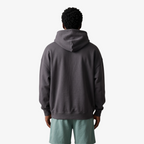 Back view of a Seejthreadsflames (STF) charcoal grey oversized heavyweight French terry hoodie on a model.