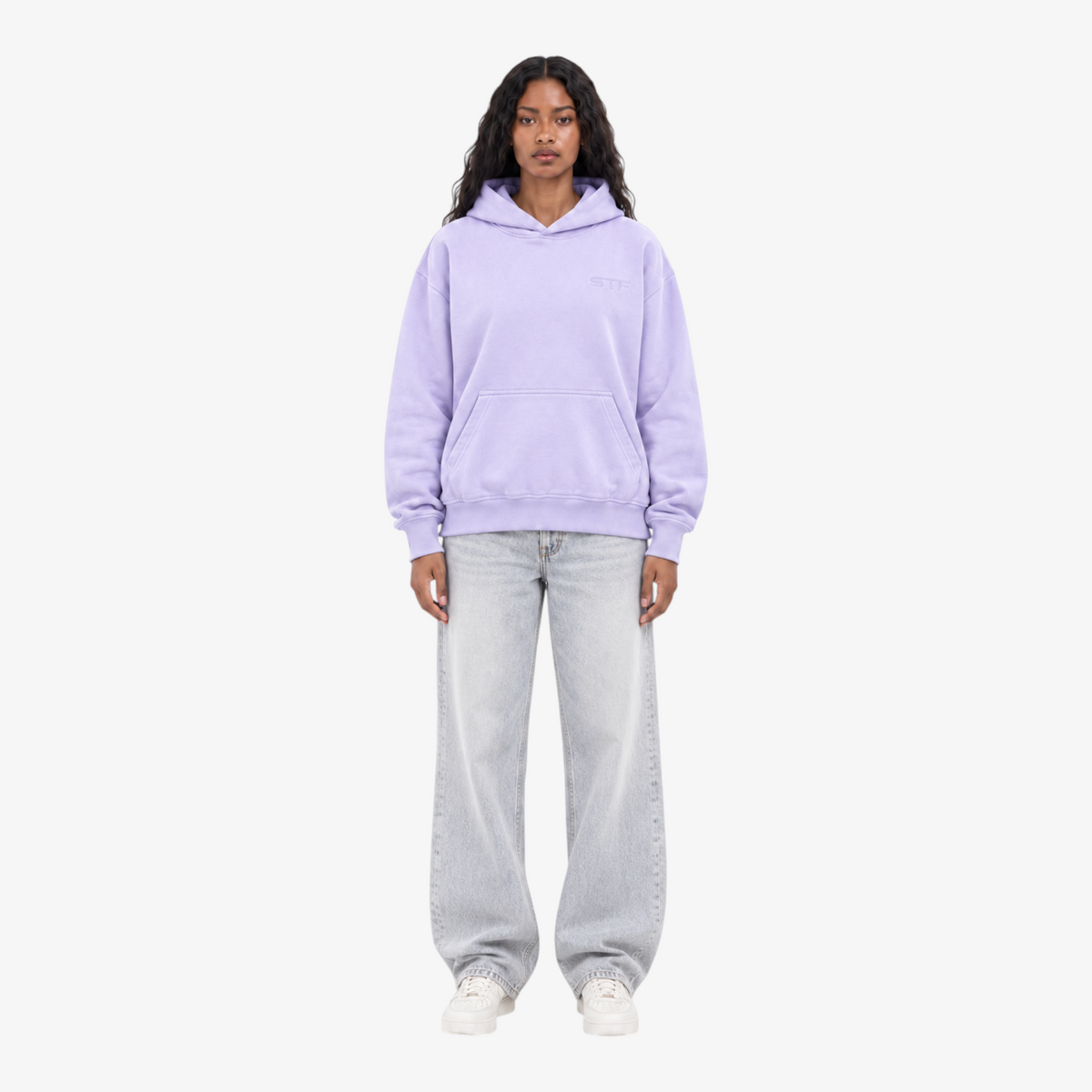 Model wearing a Seejthreadsflames (STF) lavender pullover hoodie with chest embroidery, paired with light wash jeans.