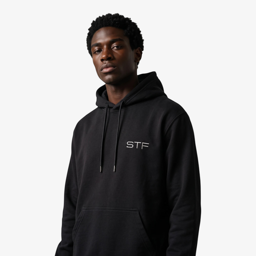 Model wearing a Seejthreadsflames (STF) black heavyweight cotton pullover hoodie with chest embroidery