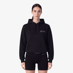 Model wearing a Seejthreadsflames (STF) black heavyweight cotton pullover hoodie with chest embroidery