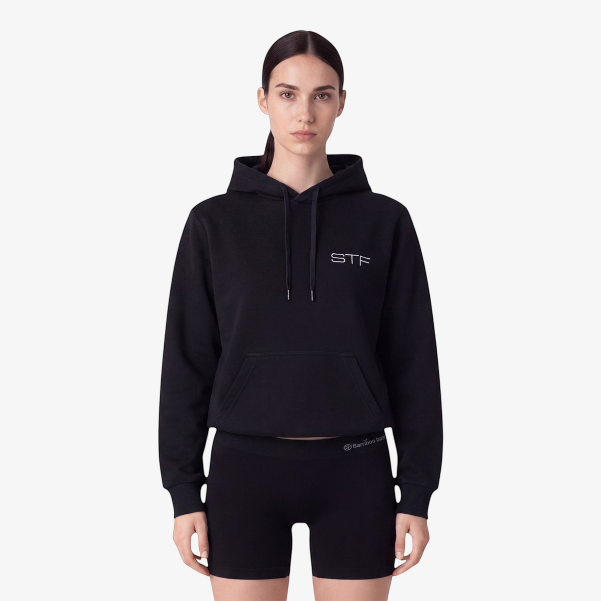 Model wearing a Seejthreadsflames (STF) black heavyweight cotton pullover hoodie with chest embroidery